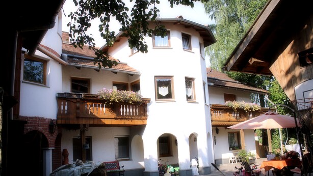 Un edificio europeo tradicional con varios balcones, un espacio de estar al aire libre cubierto y una entrada de ladrillo.