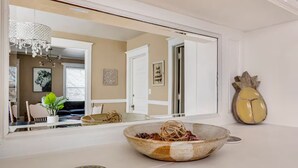 A modern bathroom with a large mirror, a decorative pineapple-shaped object, and a bowl on the countertop.