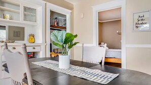 A modern room with a dining table, chairs, a potted plant, and a bed.