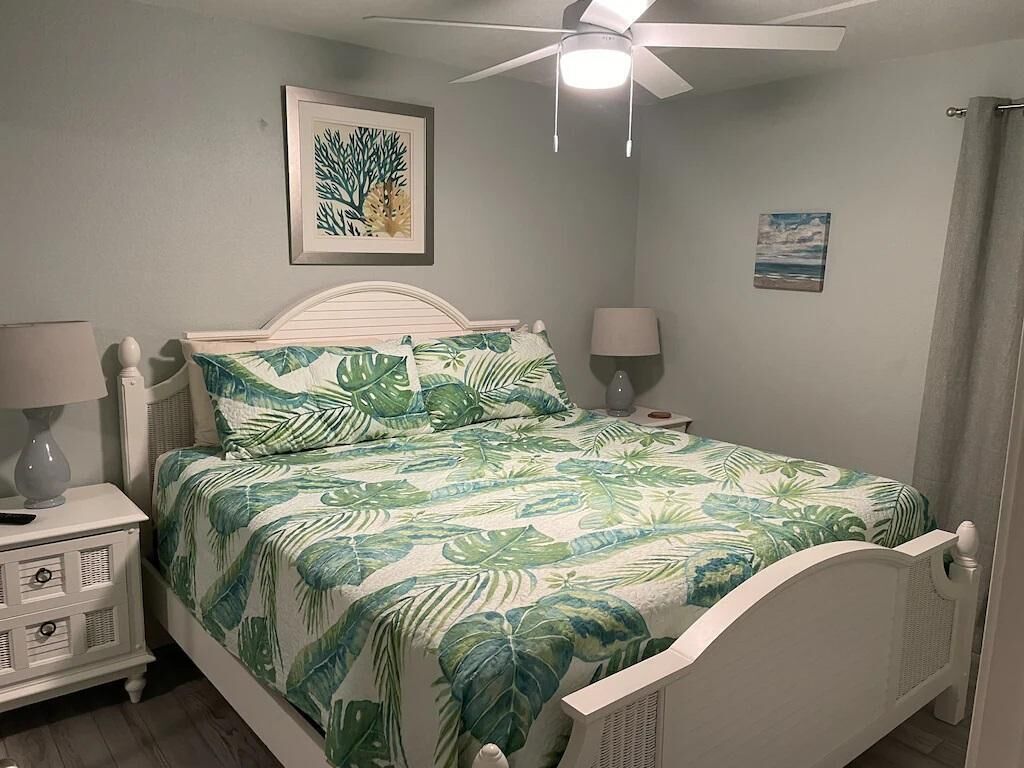 A bedroom with a bed, a nightstand, a ceiling fan, and wall art.
