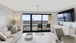 Habitación de hotel con balcón, sofá, mesa de centro y televisión.