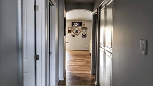 Un couloir doté d’un plancher en bois, de portes blanches et d’œuvres d’art décoratives sur les murs.