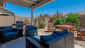 Une terrasse extérieure aménagée avec des meubles en osier, un barbecue et une table.