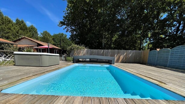 Una piscina rectangular con un borde de madera alrededor.
