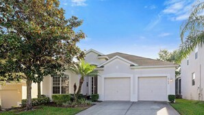 A two-story house with a front driveway, a garage, and a well-maintained lawn. - Olaf's Endless Summer at Windsor Hills (Kissimmee)