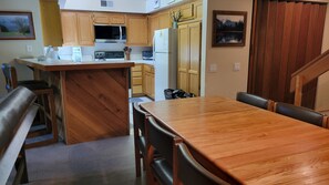 Une cuisine dotée de meubles en bois, d’un four à micro-ondes, d’un réfrigérateur et d’un coin repas avec une table et des chaises en bois.