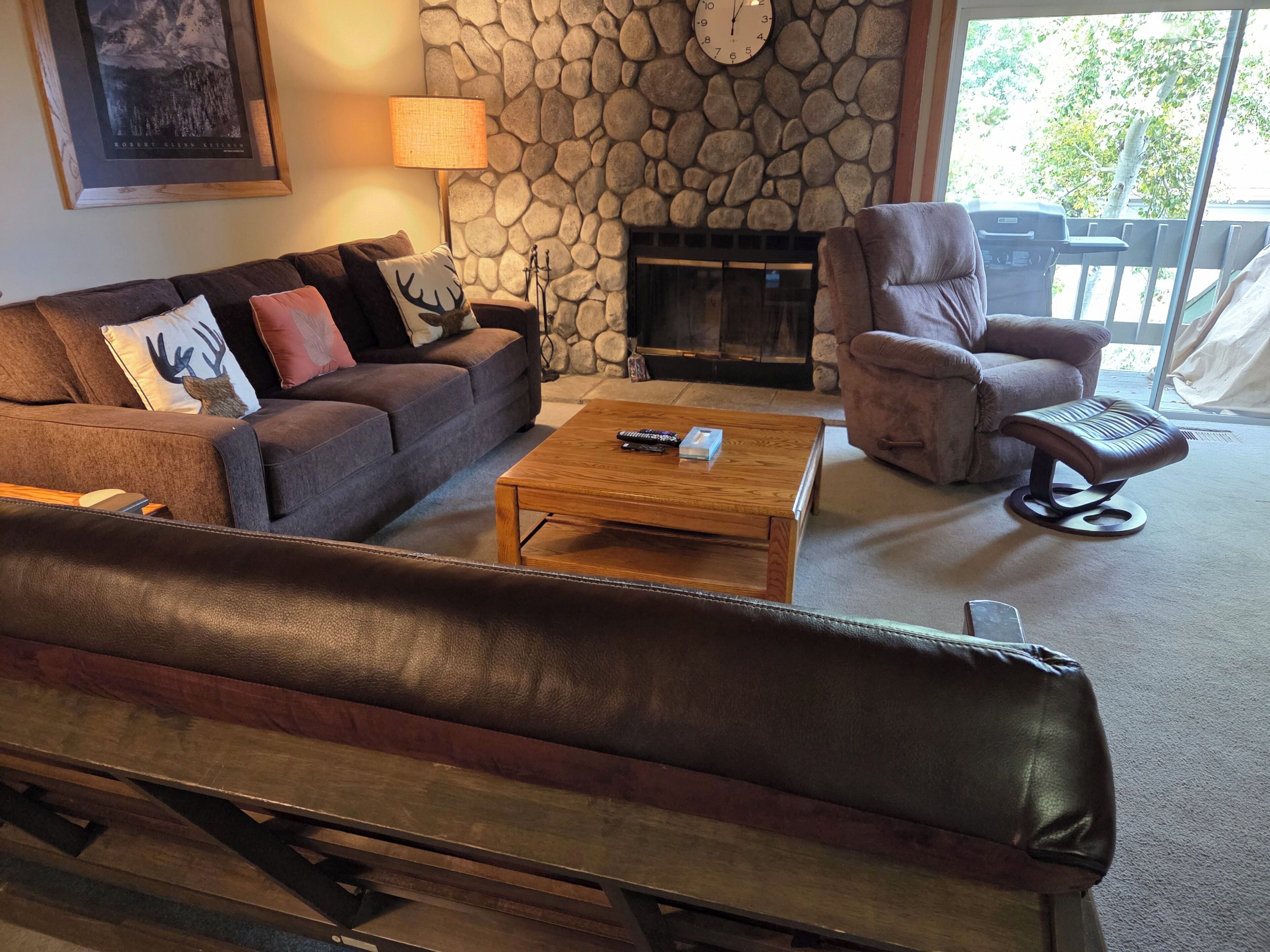 Ein Wohnzimmer mit Steinsturz, Kamin, einer Couch, einem Sessel und einem Couchtisch.