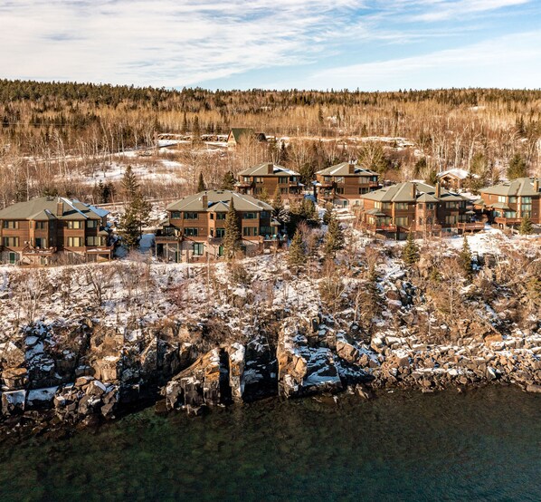 Resort com vários edifícios, primeiro plano rochoso e vegetação densa ao fundo.