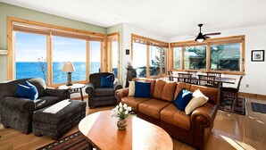 Un ampio soggiorno con vista sull'oceano, un'area pranzo con tavolo e sedie e una ventola a soffitto.