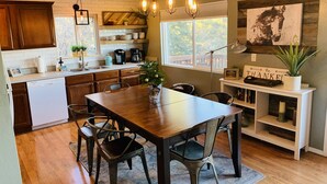 A modern kitchen with wooden cabinets, a dining table, and a large window. - Mountain View Retreat Close to Downtown Flagstaff, Big Deck, Trails Nearby! (Flagstaff)