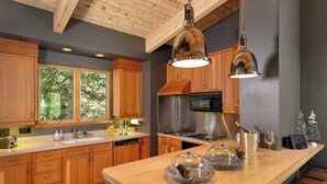 A modern kitchen with wooden cabinets, stainless steel appliances, and a large island with glass-top bowls.