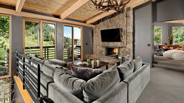 A modern living room with a stone fireplace, a large sofa, and a television mounted on the wall.