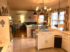 A kitchen with a central island, white cabinets, and a hanging light fixture.