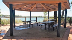 Relax in a scenic outdoor seating area overlooking the water, surrounded by picnic tables and benches.
