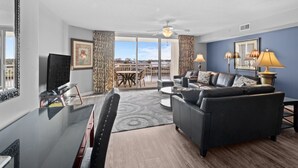 A modern living room with a black leather sofa, a glass dining table, and a ceiling fan. - Yacht Club Villas #3-502 Wonderful Waterway Views! (North Myrtle Beach)