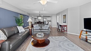 A modern living room with a leather sofa, a round coffee table, and a ceiling fan. - Yacht Club Villas #3-502 Wonderful Waterway Views! (North Myrtle Beach)