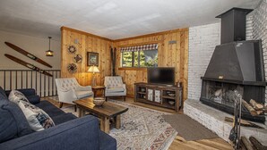 A cozy living room with a fireplace, a sofa, armchairs, and a television. - Goetzl by Hauserman Rental Group (Tahoma)