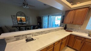 A kitchen with wooden cabinets, a marble countertop, and a backsplash. - Spacious Santa Fe 4b/4b Pool and Spa home centrally located (Lake Havasu City)