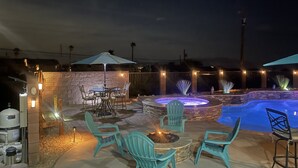 An outdoor patio area with a pool, stone walls, and outdoor furniture. - Spacious Santa Fe 4b/4b Pool and Spa home centrally located (Lake Havasu City)