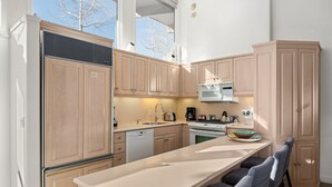Une cuisine moderne avec des meubles en bois clair, des appareils en acier inoxydable et un îlot central doté de sièges.