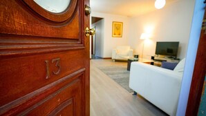 A wooden door with the number 13, leading to a living room with a white sofa, a TV, and a lamp. - Adelaide Style Accommodation - Getaway-Close to City In elite North Adelaide (North Adelaide)