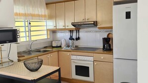 A compact kitchen with a built-in oven, a coffee maker, and a refrigerator. - Villa with private pool, terraces and direct access to the sea +Wifi (Corralejo)
