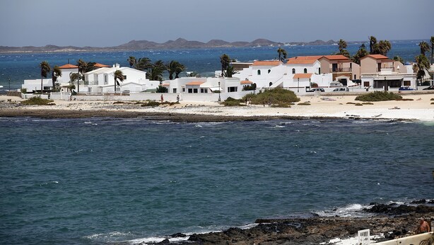 A coastal building complex with white facades and red-tiled roofs, situated near a sandy beach and the sea. - Villa with private pool, terraces and direct access to the sea +Wifi (Corralejo)