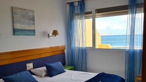 A bedroom with a large bed, a view of the sea, and a painting on the wall. - Villa with private pool, terraces and direct access to the sea +Wifi (Corralejo)