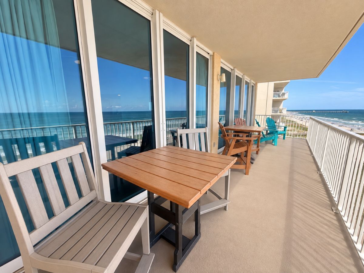 A balcony with a table and chairs, overlooking the ocean.