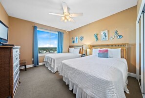 Une chambre d’hôtel avec deux lits, un ventilateur de plafond, une télévision et une vue sur la ville.