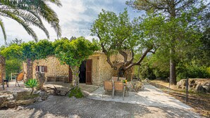A rustic stone building with a wooden door, surrounded by trees and a gravel path. -  Cottage with private pool, free WIFI, mountain views and huge garden. (Campanet)