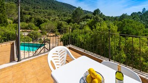 A terrace with a pool, a table with lemons and a bottle, and a view of a forested hillside. -  Cottage with private pool, free WIFI, mountain views and huge garden. (Campanet)