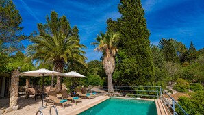 A pool area with lounge chairs and umbrellas, surrounded by trees and a clear blue sky. -  Cottage with private pool, free WIFI, mountain views and huge garden. (Campanet)