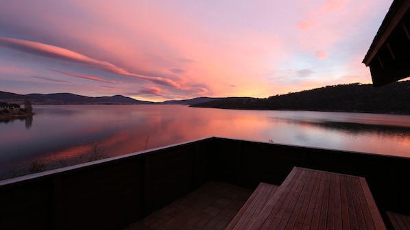 A serene lakeside view from a wooden deck with a clear sky.