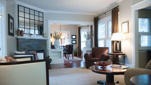 A spacious living room with a fireplace, comfortable seating, and a dining area in the background. - Beautiful Historic Old Northend Bungalow with amazing outdoor space (Colorado Springs)