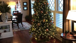 A living room with a Christmas tree, a dining table, chairs, a lamp, and a window with curtains. - Beautiful Historic Old Northend Bungalow with amazing outdoor space (Colorado Springs)