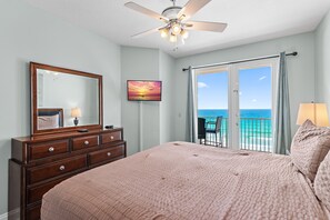 Ein Schlafzimmer mit Bett, Kommode, Deckenventilator und einem Balkon mit Meerblick.