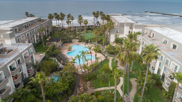 A resort with a central pool, palm trees, and a beach view. - Breathtaking Views, Steps to the Sand, Beach Resort (Oceanside)