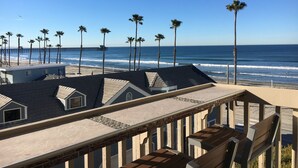 A beachfront property with a patio area, a view of the ocean, and palm trees. - Breathtaking Views, Steps to the Sand, Beach Resort (Oceanside)