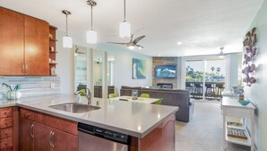 A modern kitchen with stainless steel appliances, a central island, and pendant lighting. - Breathtaking Views, Steps to the Sand, Beach Resort (Oceanside)
