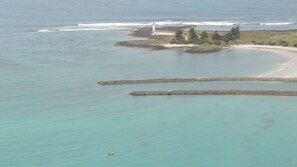 A coastal area with a lighthouse, calm waters, and a sandy beach.