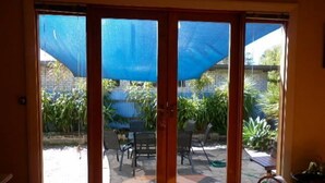 A sliding glass door leading to an outdoor patio area with a blue umbrella, outdoor furniture, and potted plants. - the whitehouse Port fairy in  the heart of town,  pet friendly (Port Fairy)