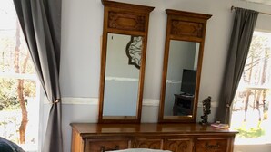 Een slaapkamer met een bed, een kast, een spiegel en een raam met gordijnen.
