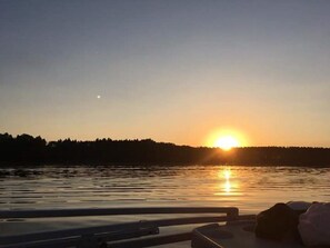 A sunset over a body of water with a silhouette of trees in the background.