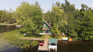 Escape to a serene lakeside retreat surrounded by lush greenery and trees, with a dock and tranquil atmosphere.