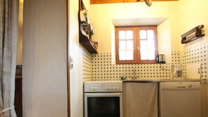 A compact kitchen with a stove, oven, and dishwasher. There is a window above the sink, and a wooden beam ceiling. - Quiet house near Saint-Lô with fireplace and garden (Bourgvallées)