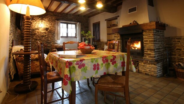 A cozy dining area with a stone fireplace, wooden beams, and a table set for two. - Quiet house near Saint-Lô with fireplace and garden (Bourgvallées)