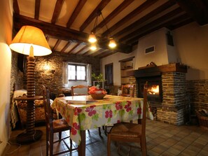 Ein gemütlicher Essbereich mit Kamin aus Stein, Holzbalken und einem Tisch für zwei Personen.