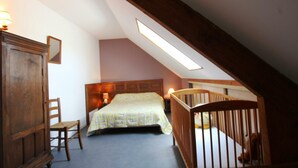A bedroom with a sloped ceiling, a bed, a crib, a chair, and a wardrobe. - Quiet house near Saint-Lô with fireplace and garden (Bourgvallées)