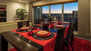 A dining area with a table set for six, large windows, and a city view.